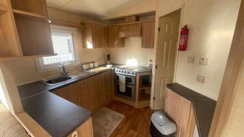a small kitchen with a sink and a stove at PG69 Golden Palm 8 Berth Caravan with Decking in Chapel Saint Leonards