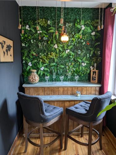 un mur vert avec une table et deux chaises dans l'établissement Les jardins de Romy, à Calais