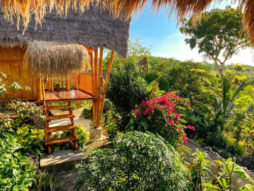 una piccola capanna con una sedia e dei fiori di Penida Bambu Green Villas a Nusa Penida