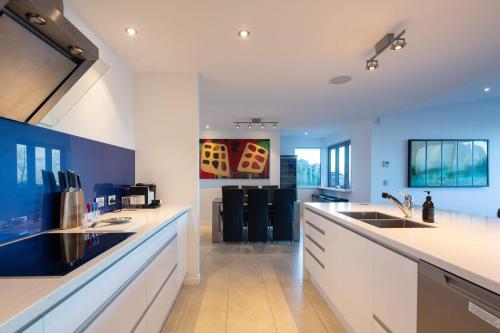 a large kitchen with white counter tops and blue walls at Alpine Edge Villa- AC- Free Parking- Hot Tub- BBQ in Queenstown