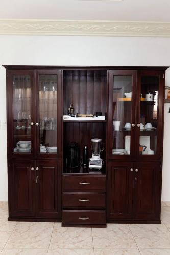a large wooden cabinet with glass doors in a room at Residencial los Reyes casa Martinez in Santiago de los Caballeros