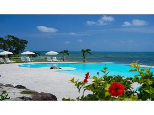 una piscina sulla spiaggia con sedie e ombrelloni di Beach Hotel Sunshine Ishigakijima - Vacation STAY 95045v a Isola di Ishigaki