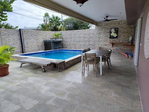 a patio with a swimming pool and a table and chairs at Tearai Iti in Paea