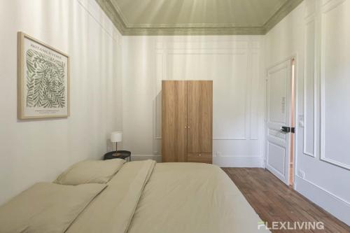 une chambre blanche avec un lit et une porte en bois dans l'établissement Flexliving - 99 Felix Faure - Whole apartment, à Paris