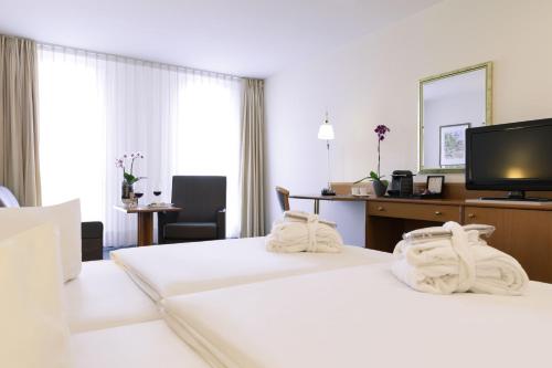 a hotel room with two beds with towels at Novotel Freiburg am Konzerthaus in Freiburg im Breisgau