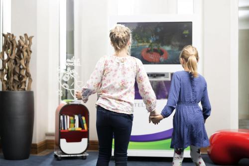a woman and a little girl playing a video game at Novotel Freiburg am Konzerthaus in Freiburg im Breisgau