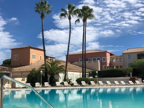 une grande piscine avec chaises et palmiers dans l'établissement Domaine de Valescure, à Saint-Raphaël
