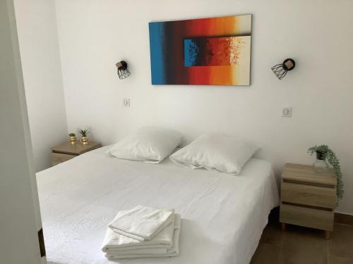 une chambre avec un lit blanc avec un tableau sur le mur dans l'établissement Domaine de Valescure, à Saint-Raphaël