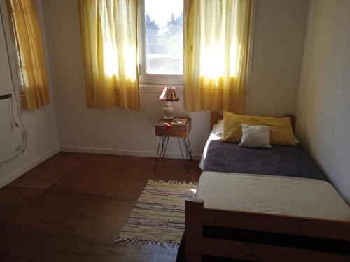 a bedroom with a bed and a window with yellow curtains at Chalet Las Doritas in La Cumbre