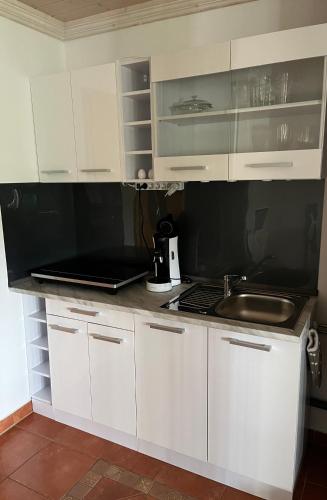 a kitchen with white cabinets and a sink at Allgäu Pension "Ab in den Süden" in Bernbeuren