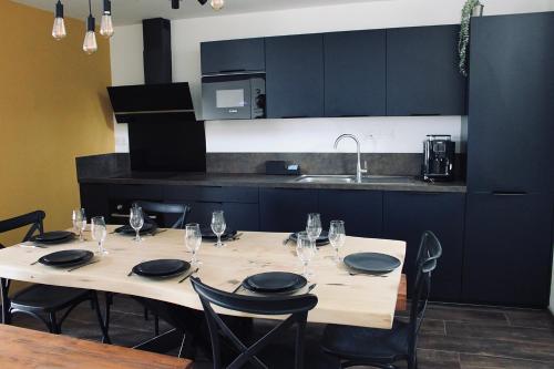 une table avec des chaises et des verres à vin, ainsi qu'une cuisine dans l'établissement Domaine Caloin - Cinéma, à Echinghen