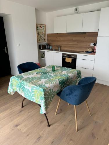 une cuisine avec une table et deux chaises ainsi qu'une cuisine avec une table et des chaises dans l'établissement Appartement cosy face à la mer, à Larmor-Plage