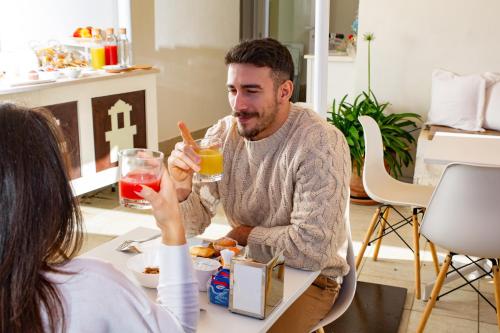 a man sitting at a table with a woman drinking orange juice at Dimora Sovrana - Urban Jungle in Matera
