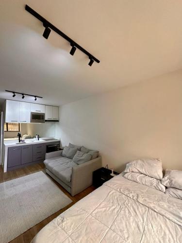 a bedroom with a bed and a couch and a kitchen at Flat Moderno no Coração do Rio in Rio de Janeiro