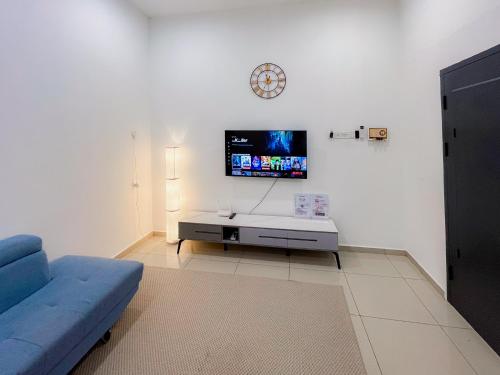 a living room with a blue couch and a tv at KotaSas Summer East Persint 5 by AHM Home in Kuantan