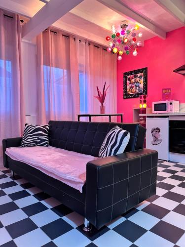 - un canapé noir dans un salon aux murs roses dans l'établissement Maison 60 m2 Loveroom romantique avec jacuzzi privé à 10 min de Nancy et jardin privé, à Messein
