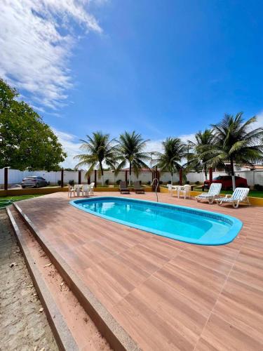 a large swimming pool with a wooden floor and palm trees at Casa Mares in Estância