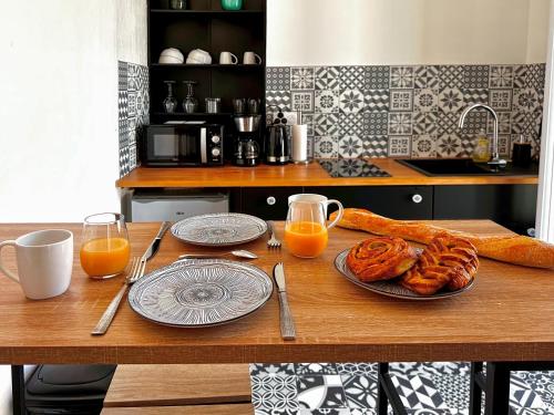 - une table avec du pain et deux verres de jus d'orange dans l'établissement Appartement entier neuf avec balcon privé - Centre Montpellier, à Montpellier
