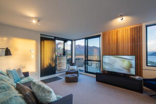 a living room with a television and a couch at Highlands Apt- Lake Views- Free Parking- AC- BBQ in Queenstown