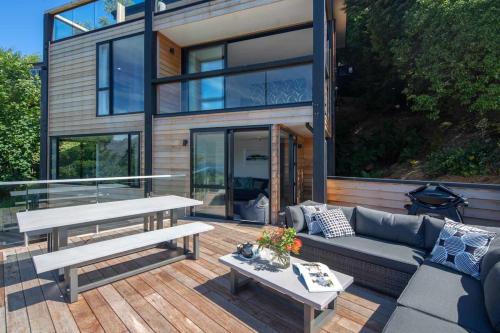 a house with a patio with a couch and a table at Highlands Apt- Lake Views- Free Parking- AC- BBQ in Queenstown