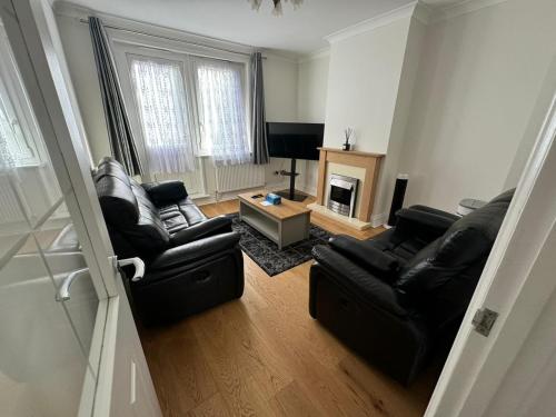 a living room with two black leather chairs and a fireplace at Homely and very comfortable apartment in London