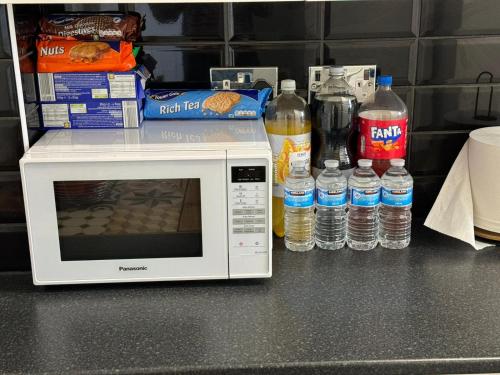 a microwave sitting on a counter with bottles of water at Homely and very comfortable apartment in London