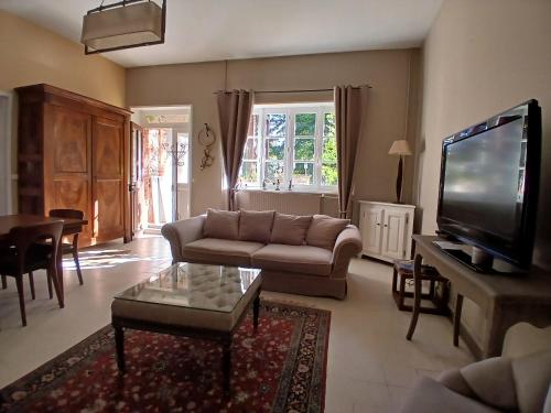 a living room with a couch and a flat screen tv at Maison ancienne à 10mn des bords de Loire in Ouzouer-sur-Trézée