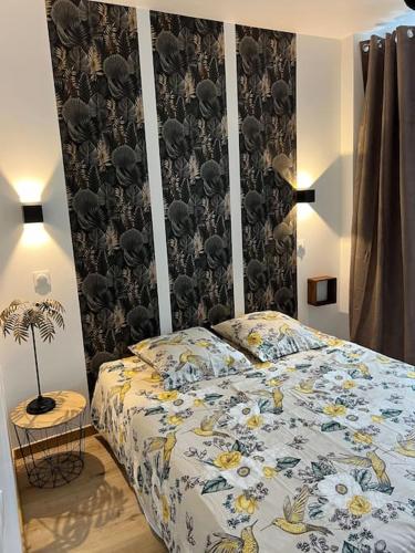 une chambre avec un lit avec un couvre-lit fleuri dans l'établissement Le Chaleureux Luchonnais, à Luchon