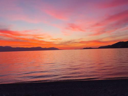 a sunset over a body of water with mountains at Home sweet home in Loutraki