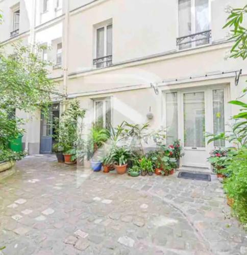 une cour avec des plantes en pot devant un bâtiment dans l'établissement Eiffel Tower Invalides Cosy Flat, à Paris