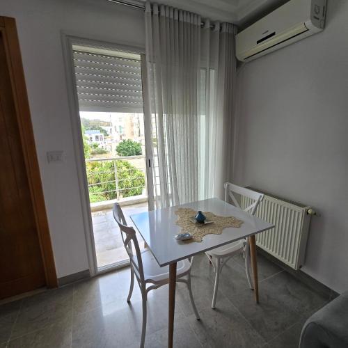a table and chairs in a room with a window at Pépite au cœur du Belvédère Tunis in Bāb as Suwayqah