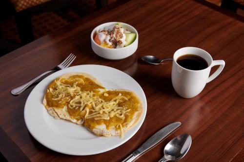 a table with a plate of food and a cup of coffee at Staybridge Suites Chihuahua by IHG in Chihuahua