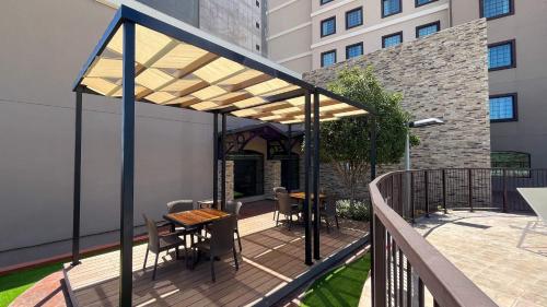 a deck with a wooden table and chairs on a balcony at Staybridge Suites Chihuahua by IHG in Chihuahua