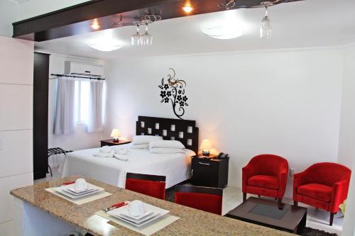 a hotel room with a bed and two red chairs at Soder Hotel in Santa Cruz do Sul