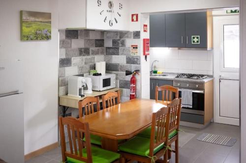 a kitchen with a wooden table with chairs and a microwave at Cantinho do Cruzeiro das Lajes in Praia da Vitória