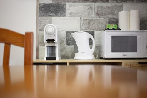 a microwave and a coffee maker on a shelf next to a microwave at Cantinho do Cruzeiro das Lajes in Praia da Vitória