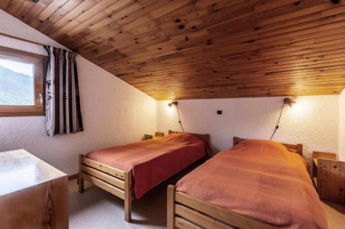 deux lits dans une chambre avec plafonds en bois dans l'établissement Résidence Pierrafort G - PIERRAFORT 35 MAE-3001, à Valmorel