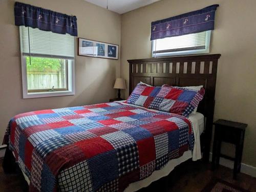 una camera da letto con un letto con una coperta a scacchi e due finestre di Baypointe Cottage 6 a Northport