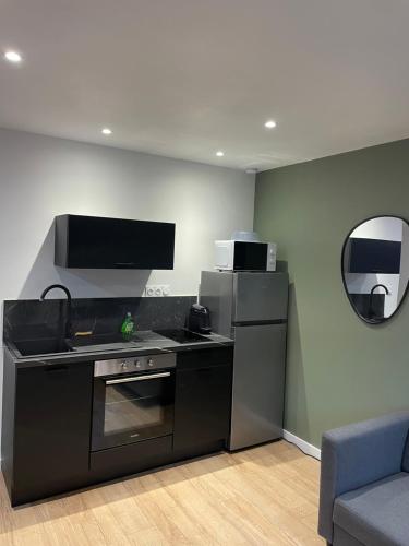 una cucina con fornelli, frigorifero e specchio di Logement atypique-Loma room a Fougères