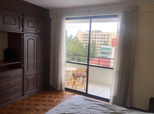 a bedroom with a large sliding glass door with a balcony at Amplio depto,parqueo,zona exclusiva in Cochabamba