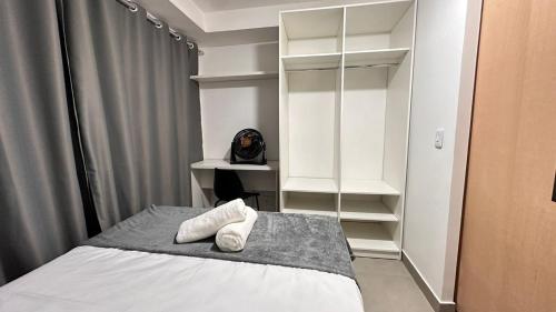 a bedroom with a bed and a desk and shelves at Kit 122 Brasília in Brasilia