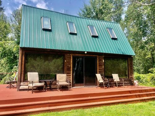 a house with a green roof and chairs on a deck at Boardman Bliss in Kingsley