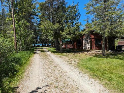 a dirt road in front of a house with trees at Trick's Lodge in Kewadin