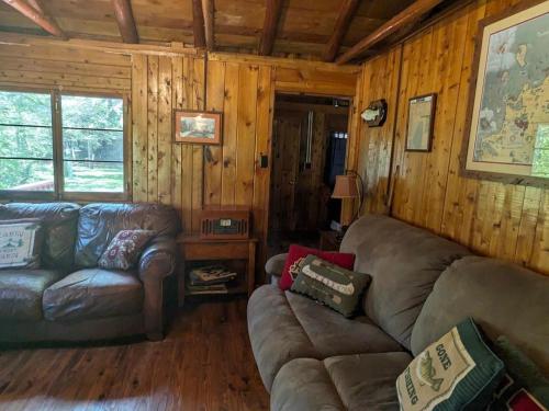 a living room with leather furniture in a wooden cabin at Trick's Lodge in Kewadin