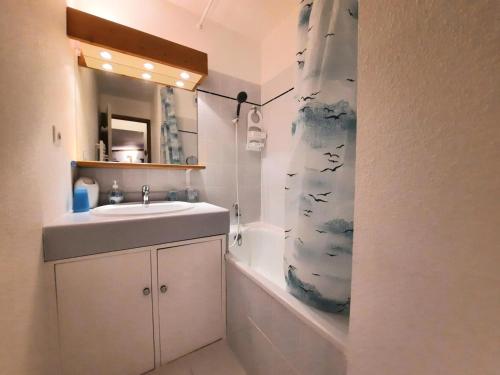 La salle de bains est pourvue d'un lavabo et d'un rideau de douche avec des oiseaux. dans l'établissement Résidence Balcons D'olympie - Appartement chaleureux avec vue sur les pistes MAE-0721, aux Menuires