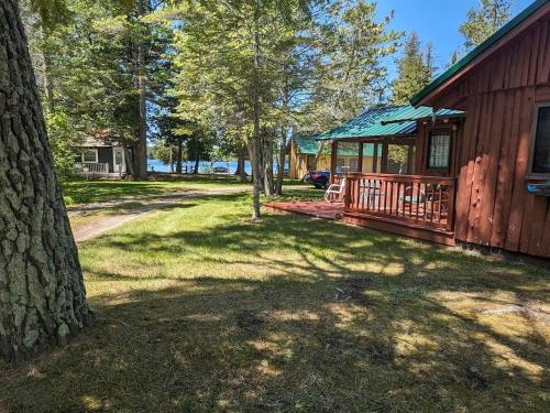 a cabin with a porch and a tree in the yard at Trick's Lodge in Kewadin