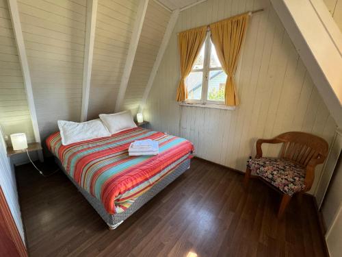 a small bedroom with a bed and a chair at Casa Orion By Los Amancays in Villa La Angostura