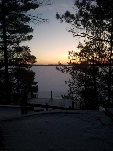 a sunset over a lake with a bench and trees at Northern Comfort 2--Long Lake-Traverse City in Traverse City