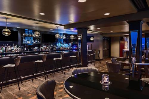 a bar with chairs and tables in a room at Ambassador Hotel Oklahoma City, Autograph Collection in Oklahoma City