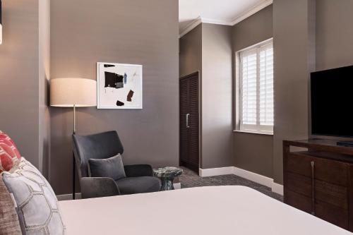a bedroom with a bed and a tv and a chair at Ambassador Hotel Oklahoma City, Autograph Collection in Oklahoma City
